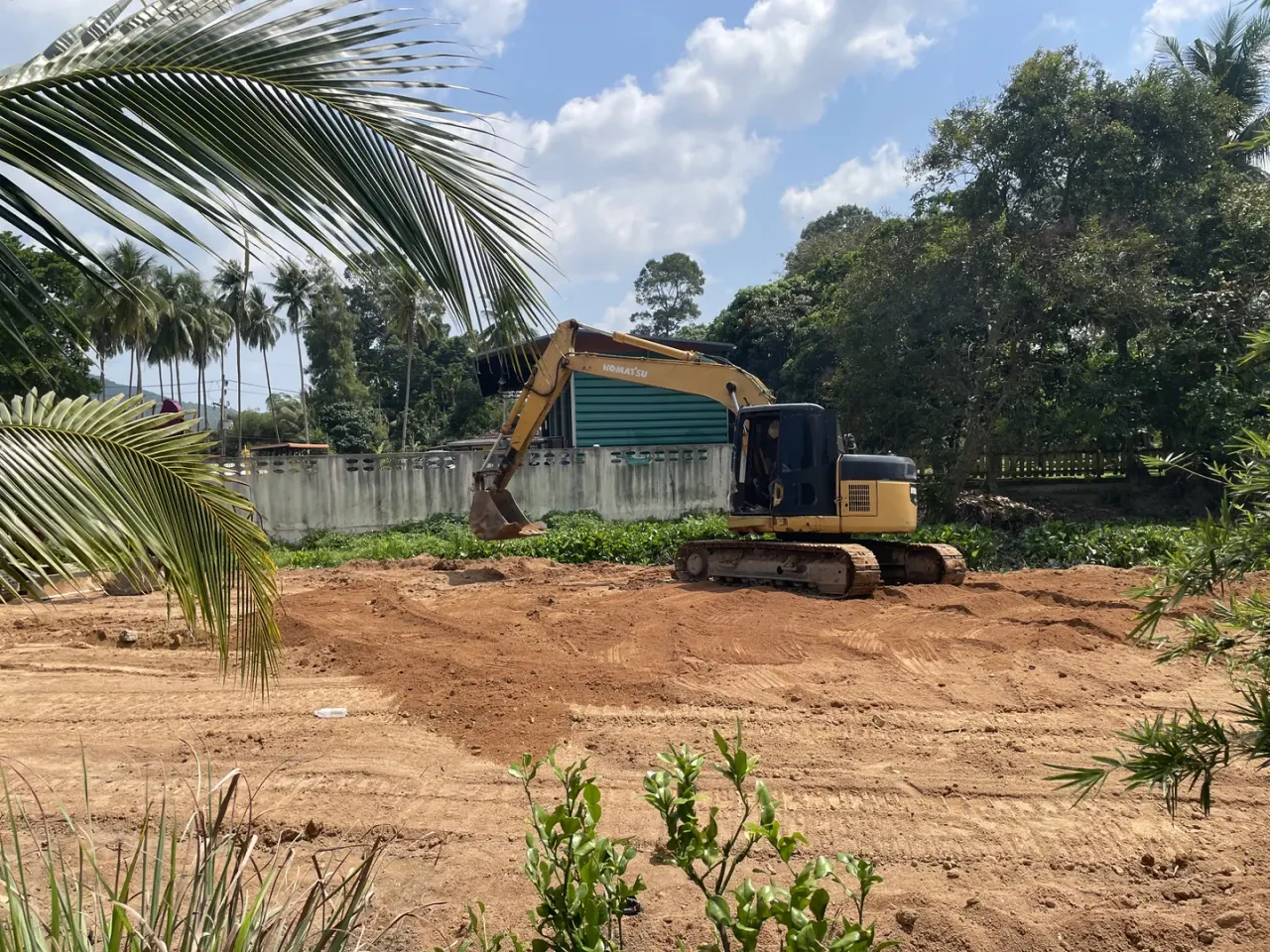 Komatsu PC128 ทำงานร่วมกับรถแทรกเตอร์เพื่อปรับระดับและบดอัดดิน