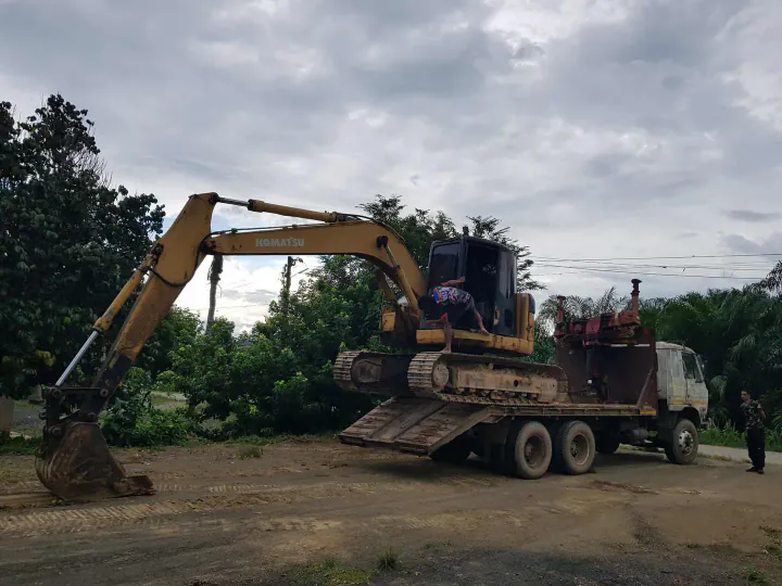 Excavator loading soil into dump truck for removal