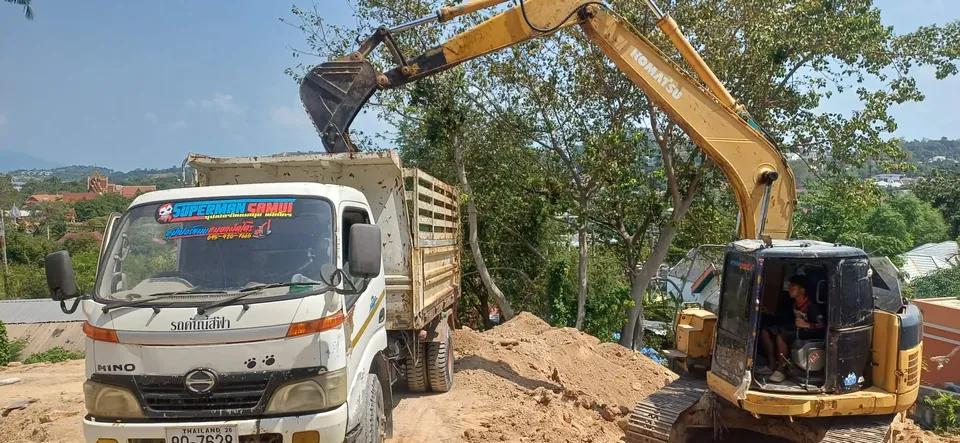 Excavator loading soil into a dump truck for removal from site